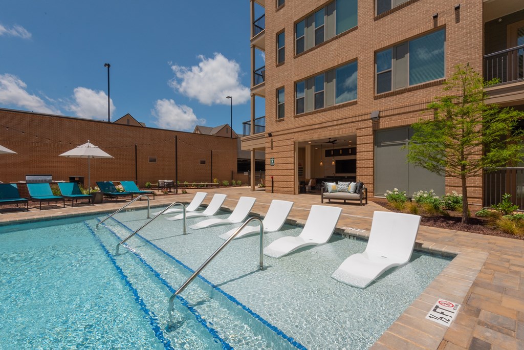 A pool with chairs and a building in the background.