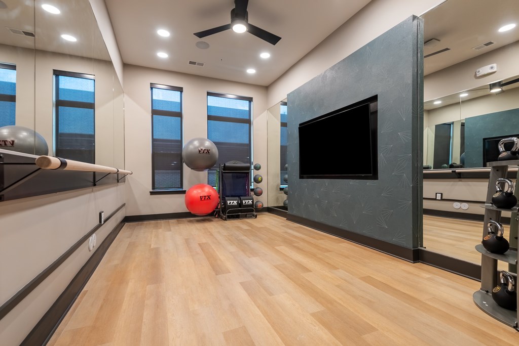 A room with wooden floors and a large TV mounted on the wall.