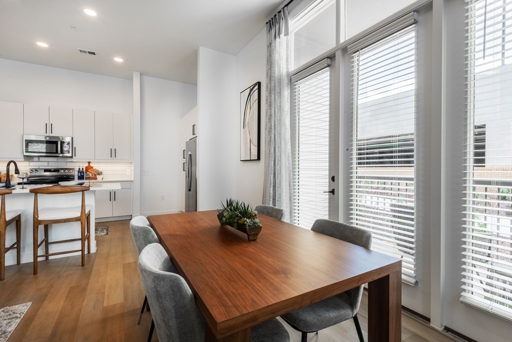A modern kitchen with a wooden dining table and grey chairs.