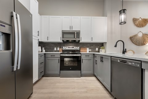 A modern kitchen with a refrigerator on the left and a sink on the right.