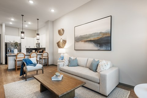A living room with a white couch, a wooden coffee table, and a painting on the wall.