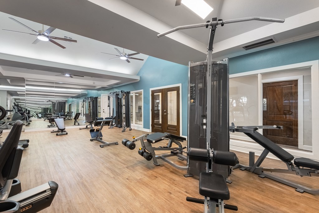 a gym with cardio equipment and weights on a wooden floor  at Hayden on West Ave, Texas