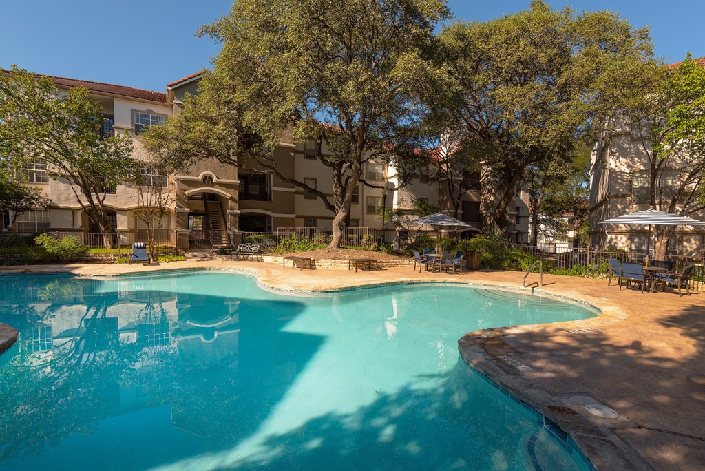 a swimming pool with trees and a building in the background  at Hayden on West Ave, San Antonio, Texas