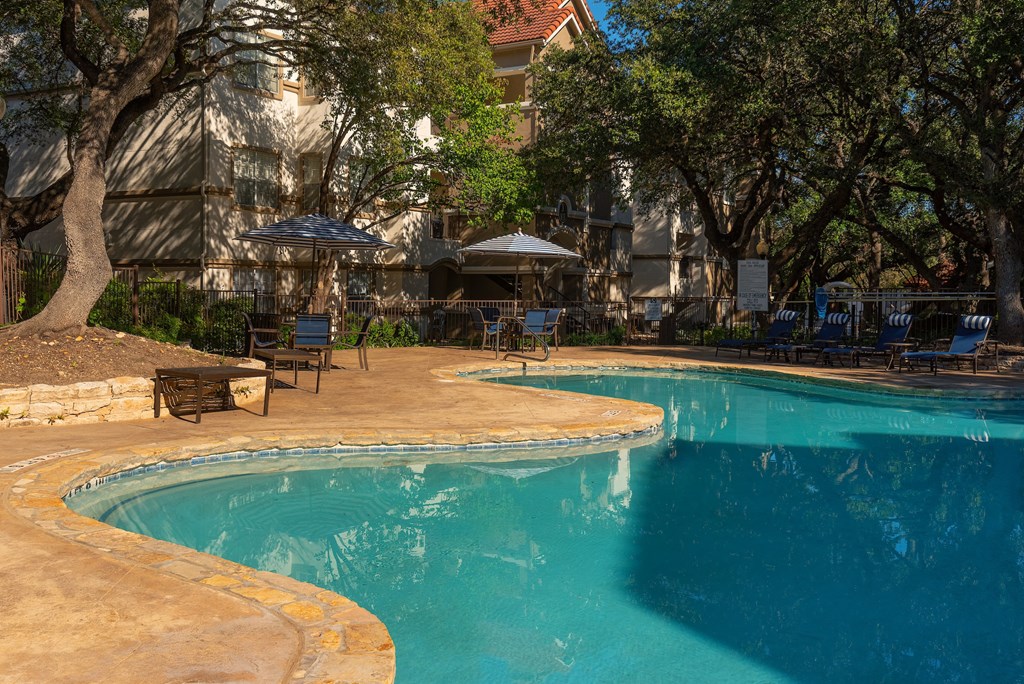 a swimming pool with chairs and umbrellas near a hotel  at Hayden on West Ave, San Antonio, Texas