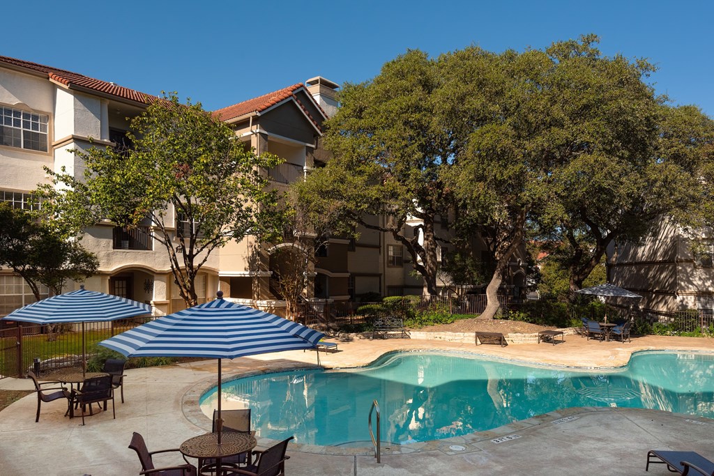 a swimming pool in front of a hotel with an umbrella  at Hayden on West Ave, San Antonio, TX