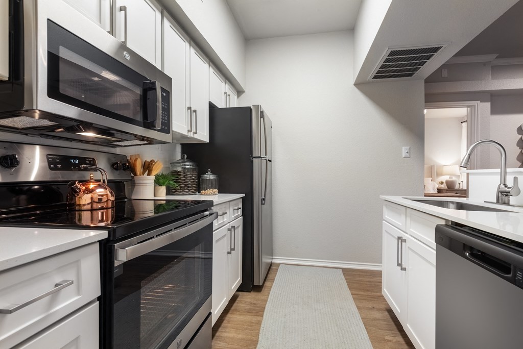 a kitchen with white cabinets and black appliances and a black refrigerator  at Hayden on West Ave, San Antonio, Texas