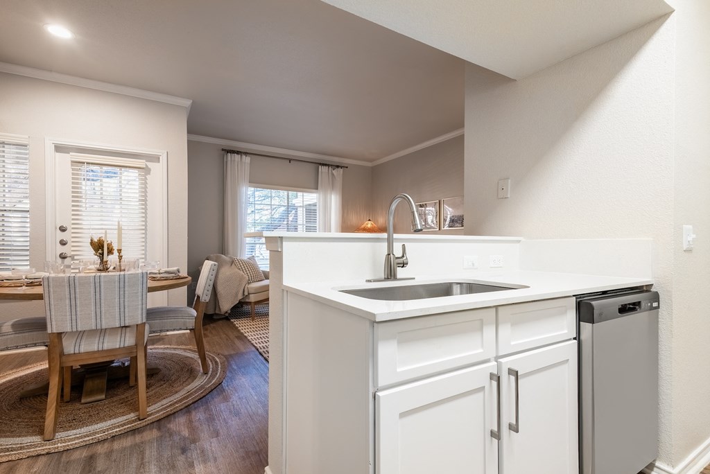 a kitchen with a sink and a dishwasher and a dining room with a table  at Hayden on West Ave, San Antonio, TX, 78216