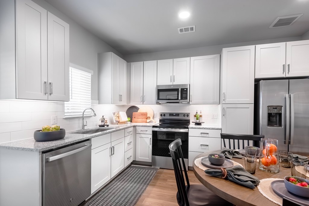 A modern kitchen with white cabinets and stainless steel appliances.