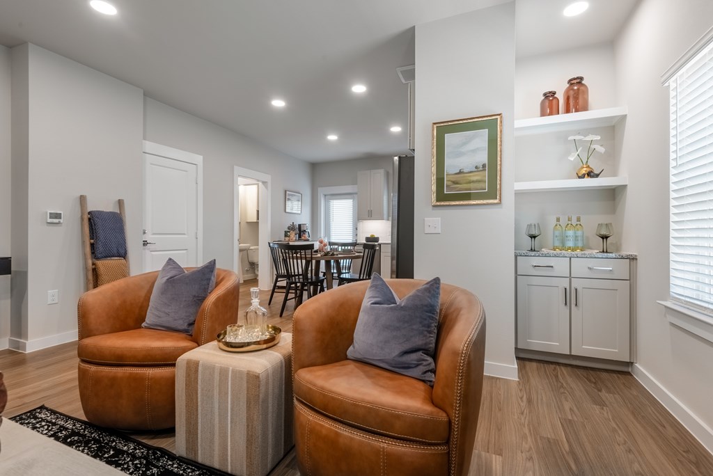 A living room with brown leather chairs and a black and white rug.