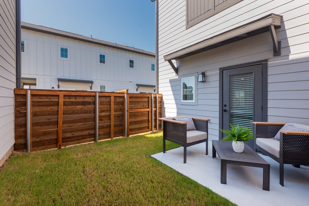 A patio with a table and chairs is in front of a house.
