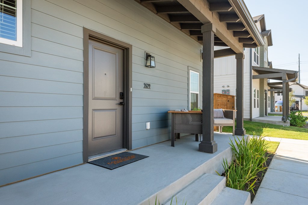 A house with a grey siding and a brown door.