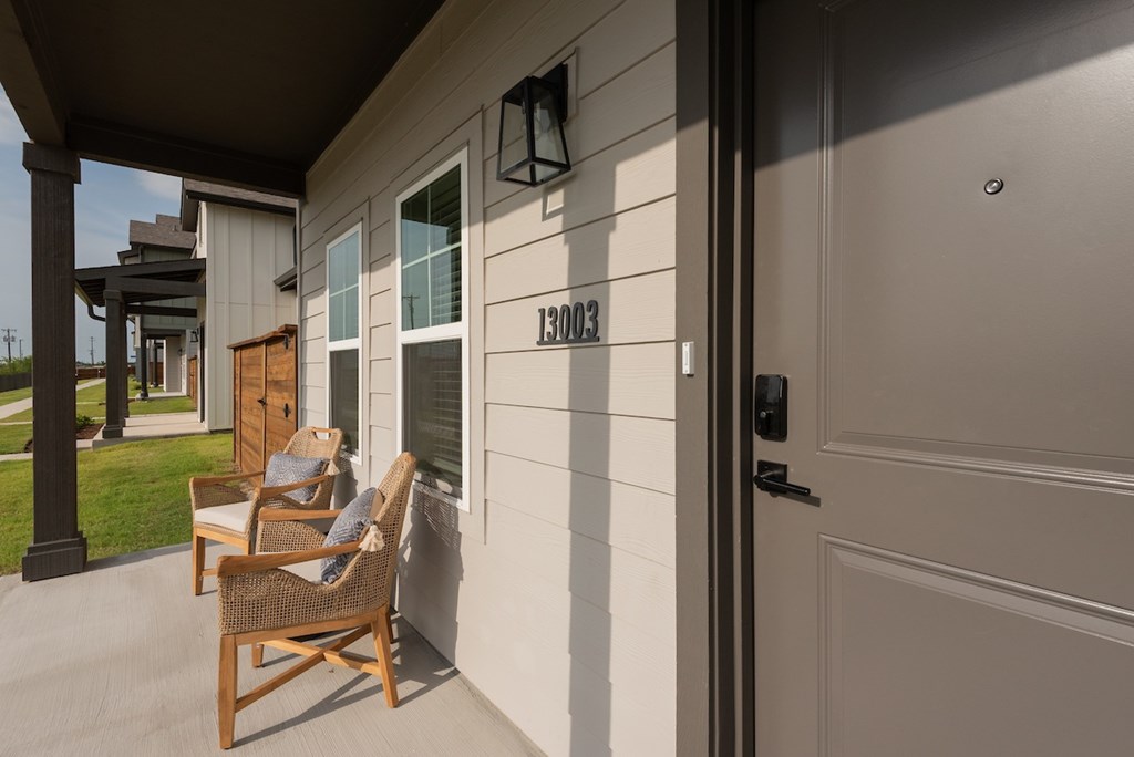 A house numbered 13003 has a porch with two chairs.