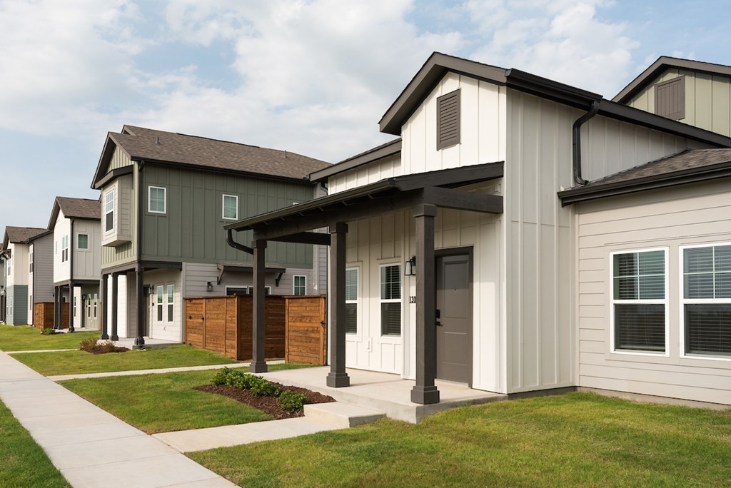A row of houses with a sidewalk in front.