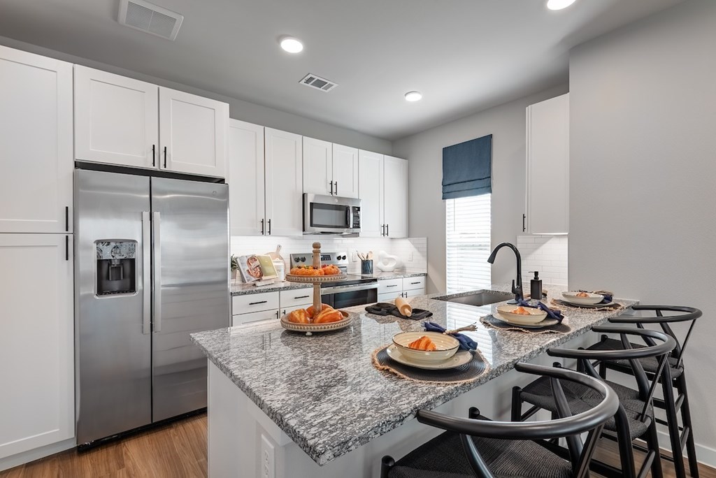 A kitchen with a granite countertop and stainless steel appliances.
