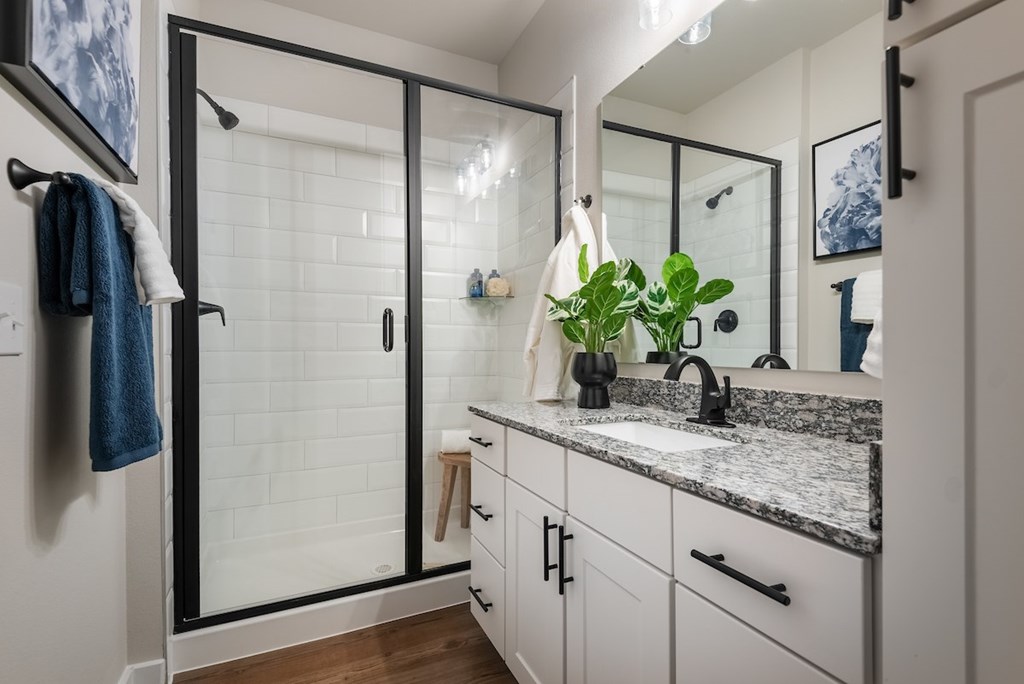 A bathroom with a white tiled shower and a marble countertop.