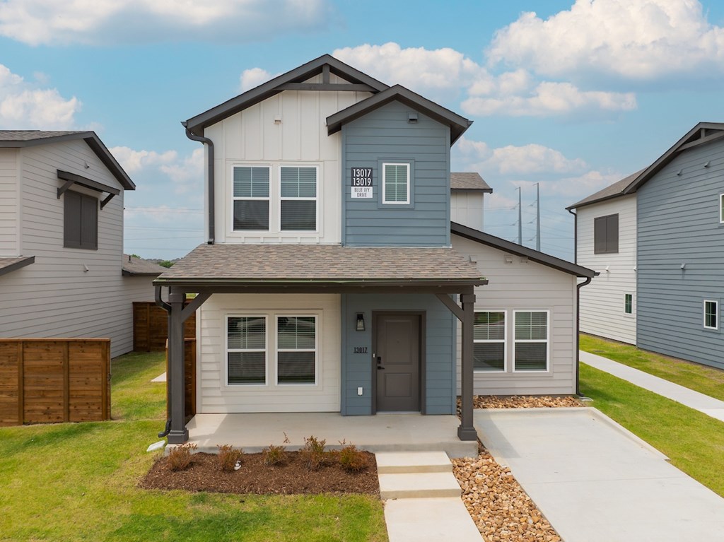 A house with a grey front yard and a grey garage door.
