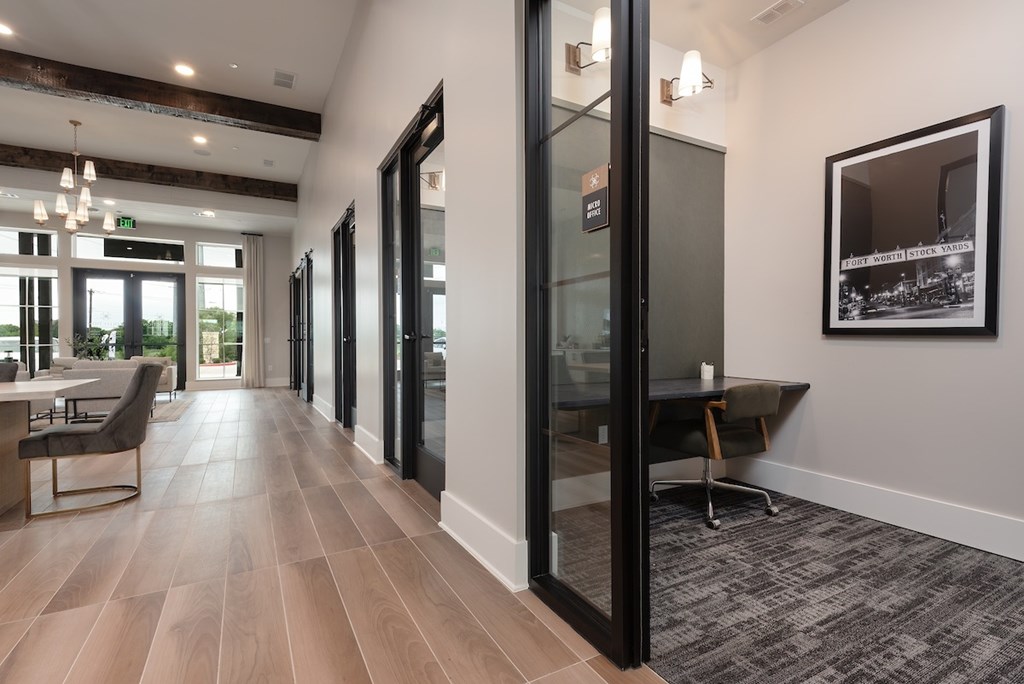 A long hallway with a chair and a table on the left and a framed picture on the wall on the right.