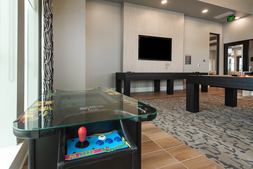 A small arcade table with a red ball on it sits in a room with a TV and a couch.