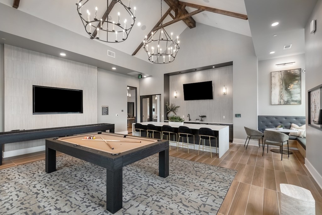 A room with a pool table and a bar area.