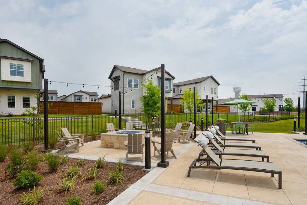 A backyard with a pool and a patio with chairs.