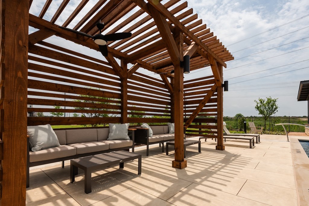 A wooden pergola with a bench and a table under it.