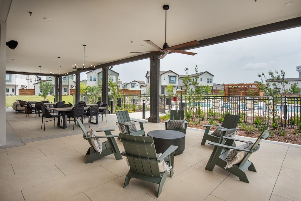 A patio with chairs and a table is covered by a roof.