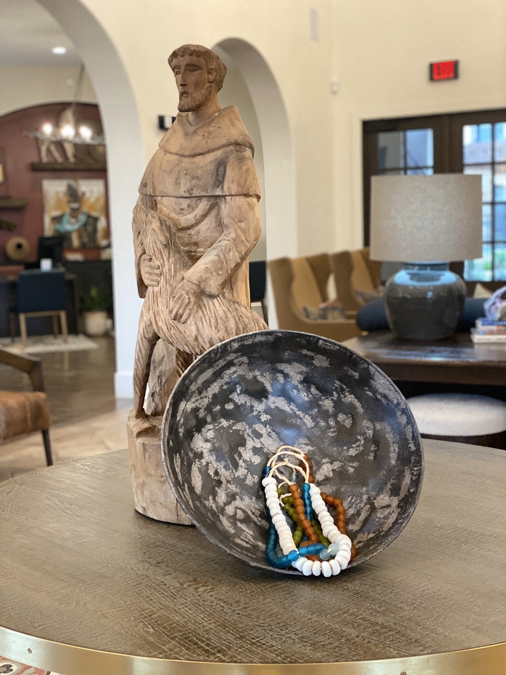 a bowl with a statue and a necklace on a table