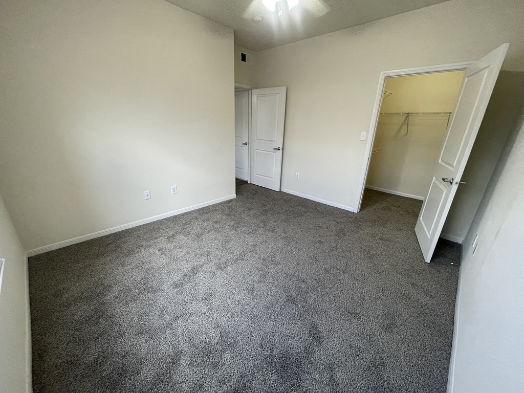 A room with carpeted floor and two doors.