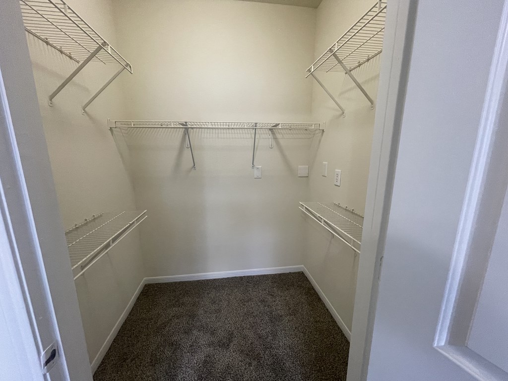 A walk-in closet with white walls and shelving.