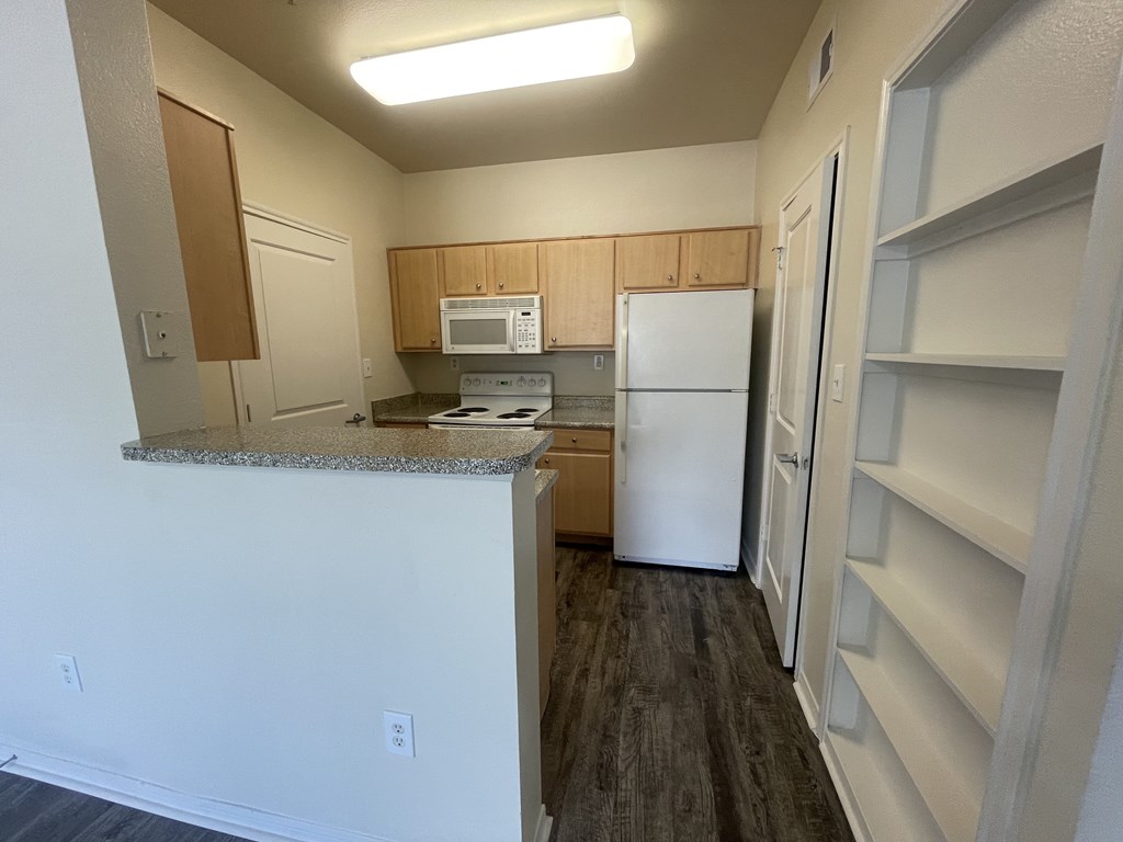 A kitchen with a white refrigerator and a microwave above the counter.