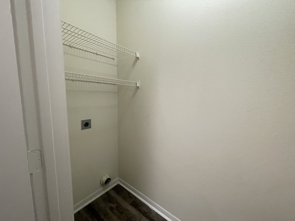 A white closet with a door open and a light switch on the wall.