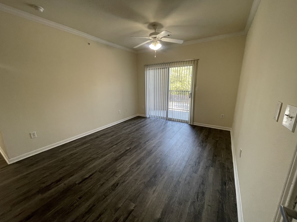 A room with a ceiling fan and sliding glass doors.