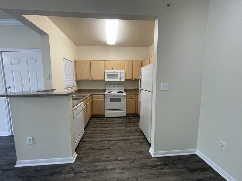 A kitchen with white appliances and wooden cabinets.