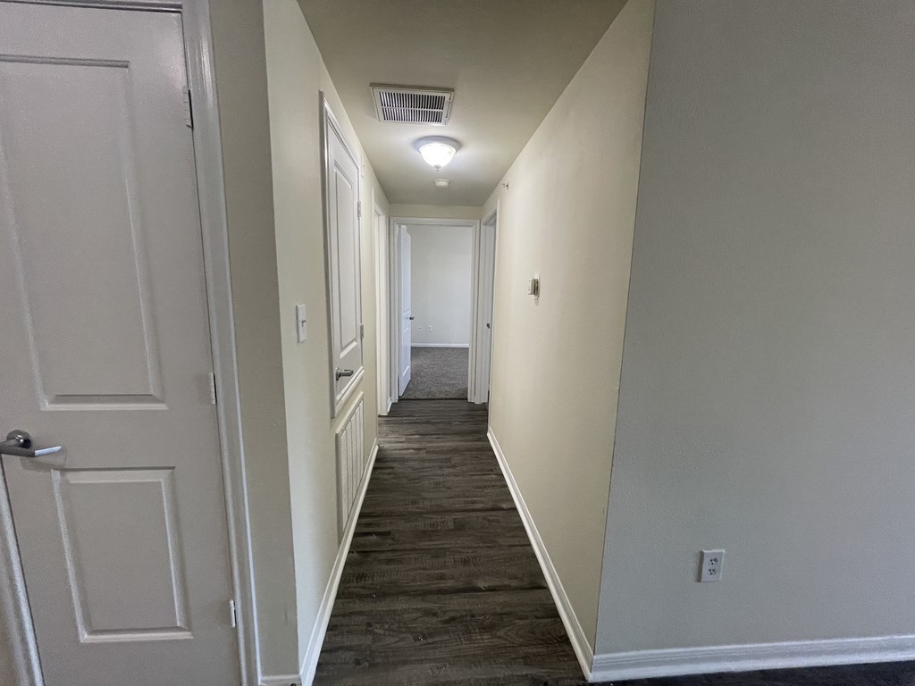 A long hallway with a door on the left and a light on the right.