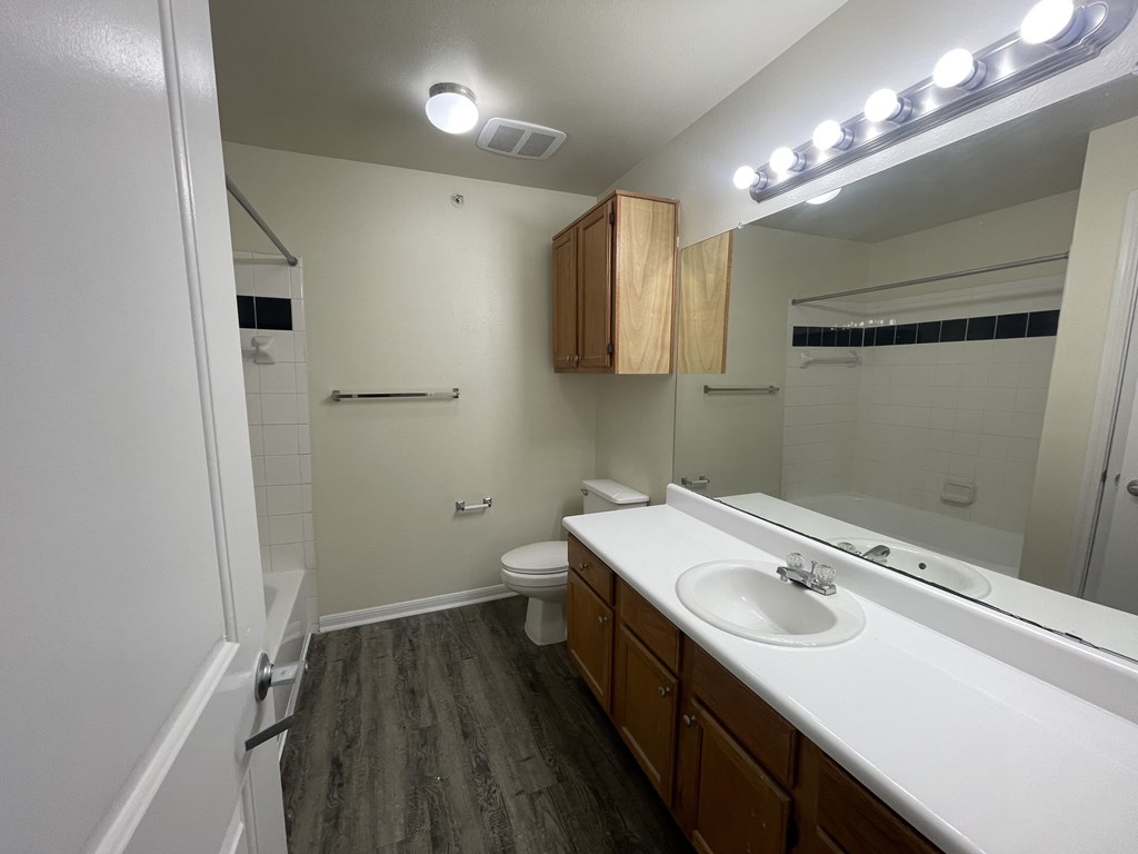 A bathroom with a toilet, sink, and mirror.