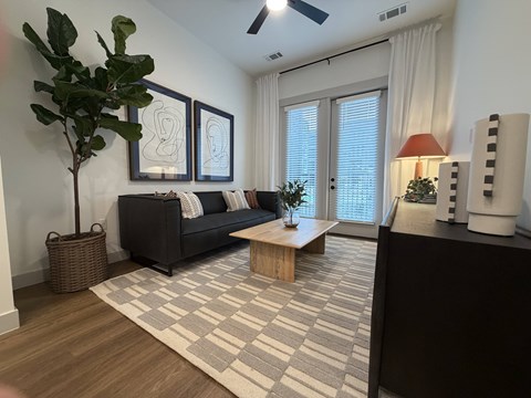 A living room with a black couch and a wooden coffee table.
