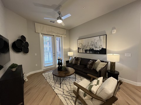 A living room with a black couch, a coffee table, and a painting on the wall.