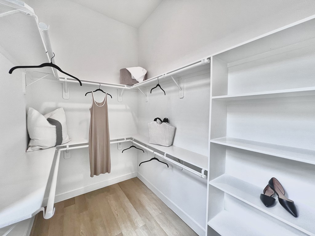A closet with a white shelving unit and a pair of black shoes on the shelf.