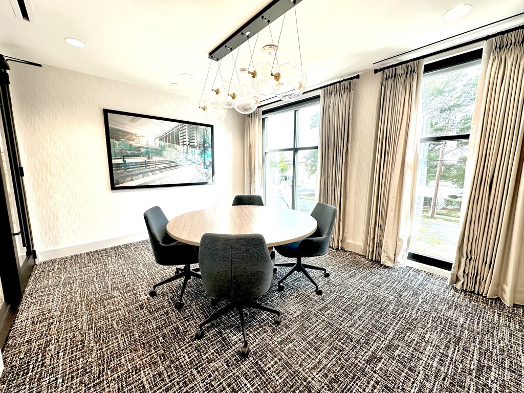 A conference room with a table, chairs, and a painting on the wall.