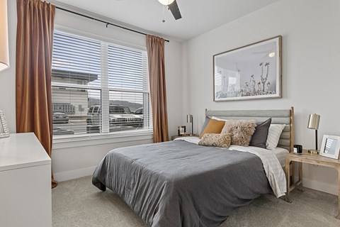 A bedroom with a large bed and a window with brown curtains.