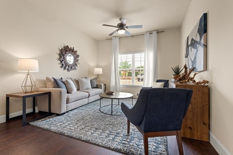 a living room with a couch and a chair and a ceiling fan