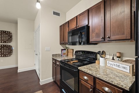 a kitchen with black appliances and granite counter tops and wooden cabinets