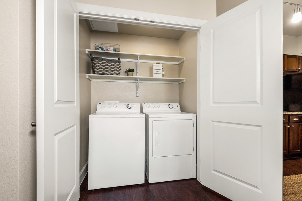 a laundry room with a washer and dryer and a closet with shelves