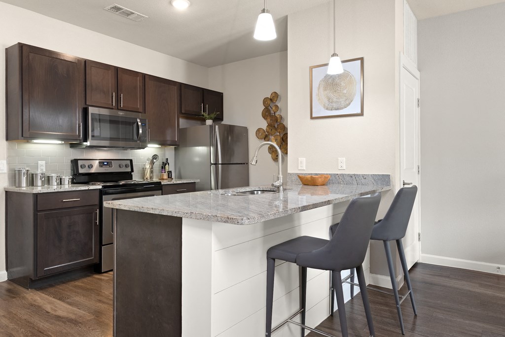 an open kitchen with a marble counter top and stainless steel appliances