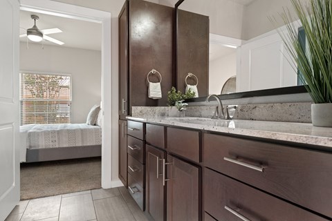 a bathroom with a sink and a mirror and a bedroom with a bed