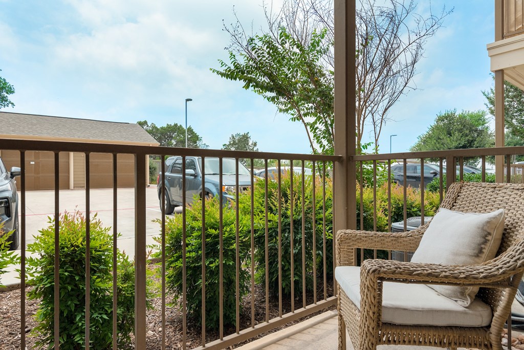 a porch with a wicker chair and a view of a parking lot