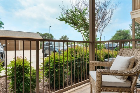 a porch with a wicker chair and a view of a parking lot