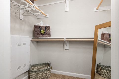 a walk in closet with shelves and baskets and a mirror