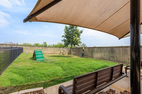 a backyard with a grass lawn and a fence and a bench