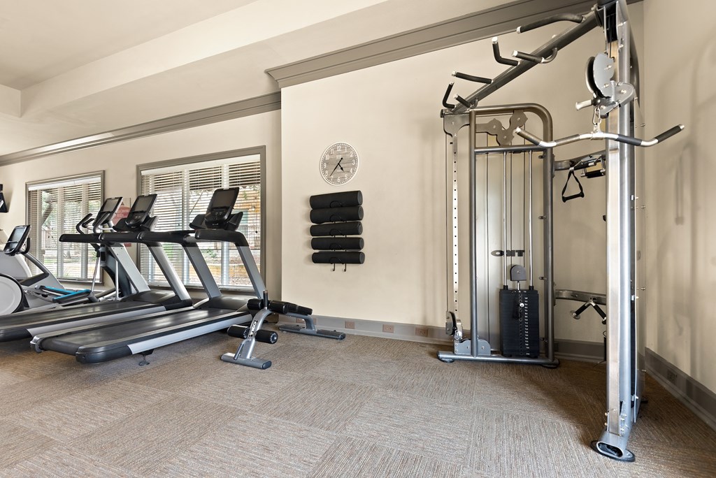 a gym with treadmills and weights in the corner of a room